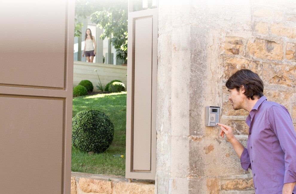 Un homme sonne et parle à l'interphone avec un portail de maison