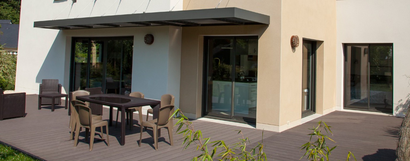 Pergolas au dessus d'une terrasse de maison avec table de salon